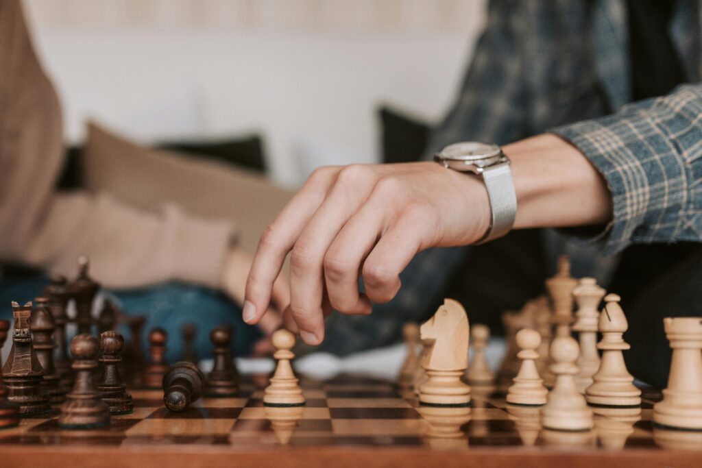 A person makes a strategic move in a chess game, highlighting the art of strategy.